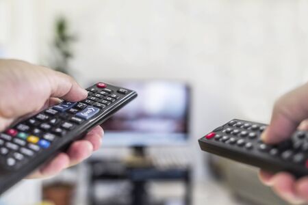 Watching tv and using two remote controlの写真素材