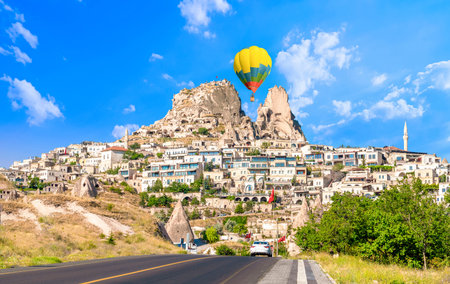 Uchisar castle, one of the most famous landmark in Turkey and one hot air balloon getting close to the castle.のeditorial素材
