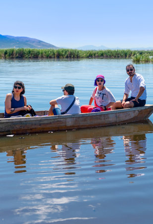 Cay, Afyonkarahisar/Turkey-June 30 2019: Tourists on fishing boat in a calm lake water. Old wooden fishing boat. Fishing boat at Lake Eber.のeditorial素材
