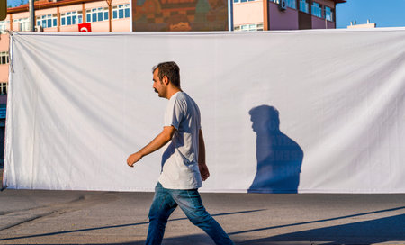 Ankara/Turkey-June 23 2019: A pedestrian walking with his shadow on the white background