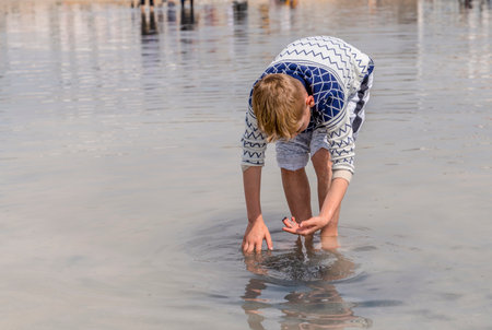 Ankara/Turkey- April 06 2019: Young boy picks salt crystal under the water in Salt Lake (Turkish: Tuz Golu)のeditorial素材