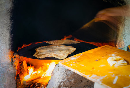 Hand making gozleme bread on wooden fire with motion blur in rural  region in Turkey