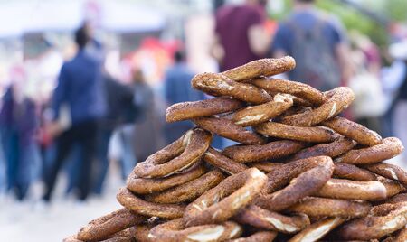 Photo of fresh bagels, buns on street. Traditional turkish street food. Simit for sale from Street vendor. Blurred people in background in a busy day.の写真素材