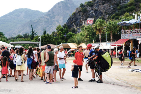 Fethiye, Mugla/Turkey- August 19 2018: Tandem paragliders unfasten parachute after landing and friends congratulate them in Oludeniz beach.のeditorial素材