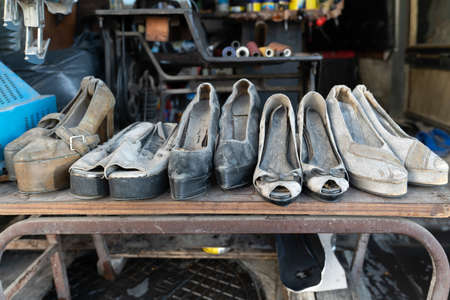 Worn high-heeled women's shoes on display in a shoe repair shopの写真素材