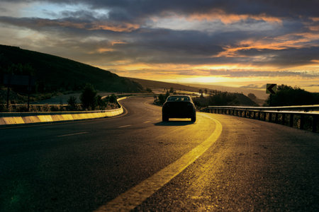Back vies of car driving on winding road at sunrise