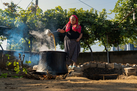 Ankara, Turkey-  September 18 2021: Molasses is made by boiling grapes at high temperatures in cauldrons. Woman makes molasses (pekmez in Turkish).のeditorial素材