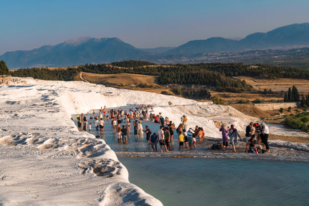 Pamukkale, Denizli, Turkey - August 26 2021: Tourists walking barefoot on travertine at sunset.のeditorial素材