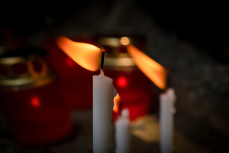 Composition burning white candle. In the background, a blurred background with burning candles, beads. concept of magic, faith.の写真素材