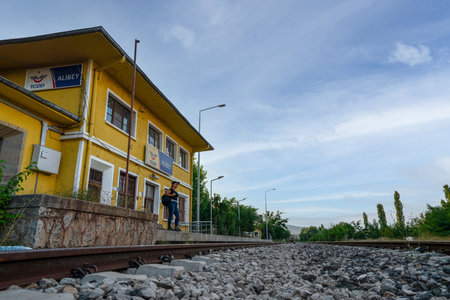 Kalecik, Ankara, Turkey- September 18 2021: Far view of woman passenger waiting at yellow colored Alibey train station building.のeditorial素材