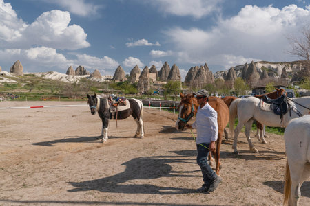 Goreme, Nevsehir, Turkey - April 24 2022: Horses for tourists to ride. Groom checks the horses.のeditorial素材