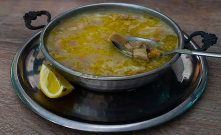 Tripe soup in a copper bowl and pieces of tripe in a spoon in a soupの写真素材