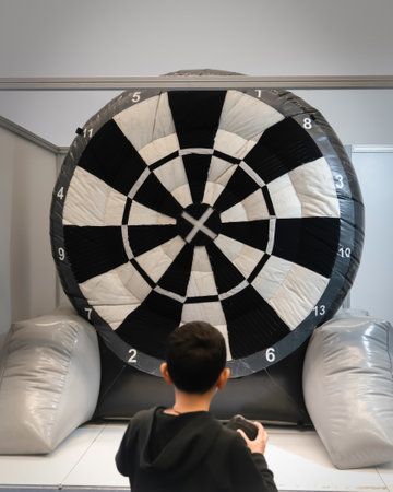 Back view of boy having fun with giant inflatable dart board.の写真素材