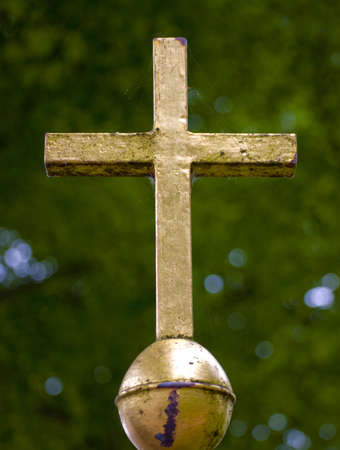 Golden cross in front of greeneryの写真素材