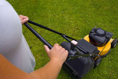 Woman mowing lawn, focus on mowerの写真素材