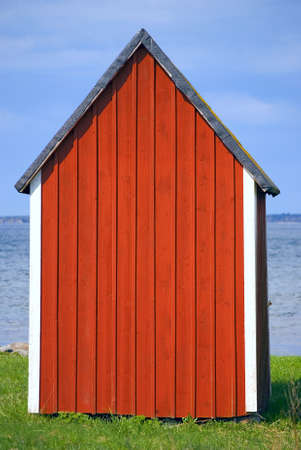 Red boathouse with blue sky and water in backgroundの写真素材