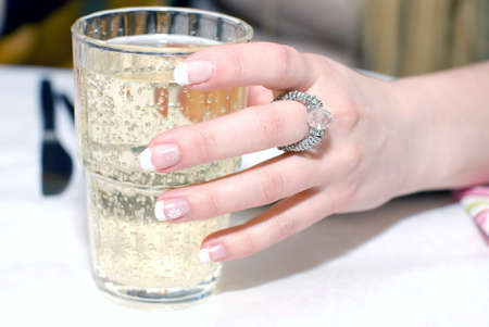 Close up of female hand, holding the glass with sparkling beverageの写真素材