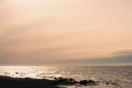 Dark stone beach, ocean and evening skyの写真素材