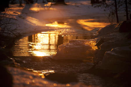 Sun reflected in the river, sunset when winter turns into springの写真素材