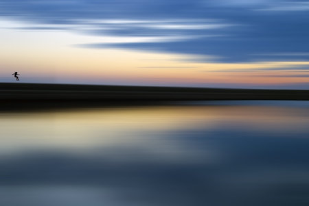 Girl jumping from pier, abstract sunset with motion in background