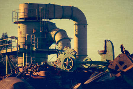 Machine behind the scrap heap works with fragmentation of the metal, aged and worn vintage style photoの写真素材