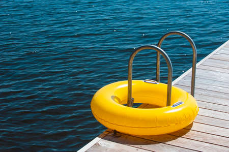 Yellow swimming ring on bath ladderの写真素材