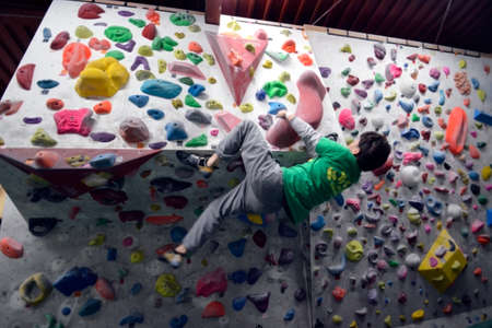 A Japanese man is climbing on practice wall indoors. View from side.の写真素材