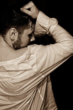 young man in a wet shirt on a black backgroundの写真素材