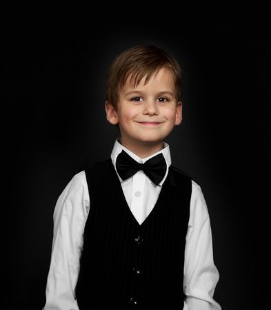 Boy in a suit smiles  isolated on black backgroundの写真素材