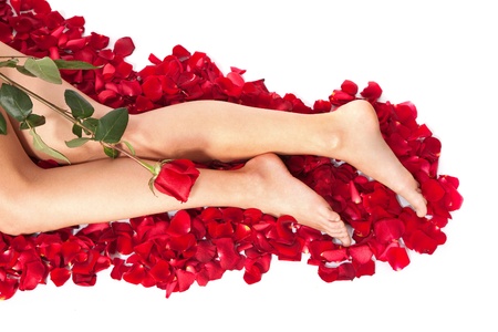 Beautiful body of woman against petals of red roses with flowerの写真素材