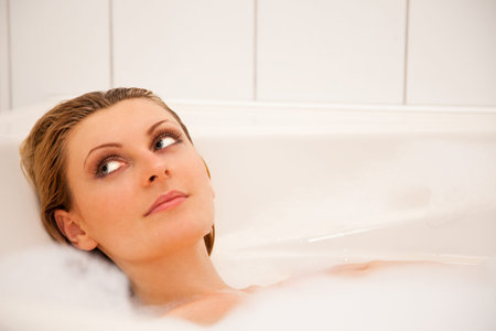 Young beautiful girl is relaxing in a bathtub with foam 