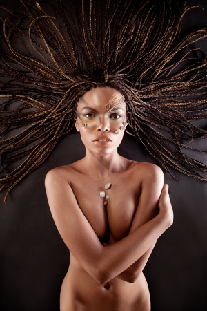 Portrait of a beautiful naked young african american woman with dreadlocks hair lying  
on a black backgroundの写真素材