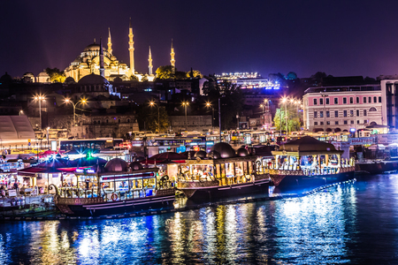 ISTANBUL - APRIL 30: Night view on the restaurants at the end of the Galata bridge, Sultanahmet, at sunset with the famous Suleymaniye Mosque in the background, Istanbul, Turkey, APRIL 30, 2013のeditorial素材