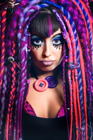 Portrait of a stylish young woman with multicolored dreadlocks and with stylish make-up in doll style. Creative make-up.Fantasy dress.の写真素材