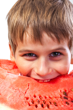 Boy is eating a watermelon isolated on a white backgroundの写真素材