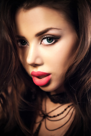 Sensual brunette woman posing, looking at camera.Long curly healthy hair on a metallic backgroundの写真素材