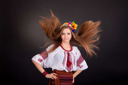 Attractive woman wears Ukrainian national dress isolated on a white background. Portrait of a beautiful girl with flying brown hairの写真素材