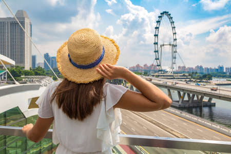 SINGAPORE, SINGAPORE - FEBRUARY 26, 2020: Woman traveler looking at  Singapore Flyer - a giant Ferris wheel in Singapore in a sunny dayのeditorial素材