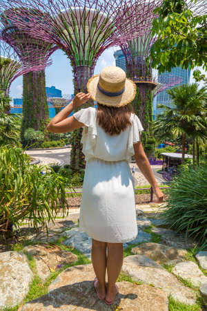 SINGAPORE - JUNE 23, 2019: Woman traveler wearing white dress and straw hat at Gardens by the Bay in Singaporeのeditorial素材