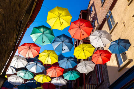 QUEBEC, CANADA - APRIL 2, 2020: Colorful umbrellas hanging over a street in old Quebec city in a sunny day, Canadaのeditorial素材