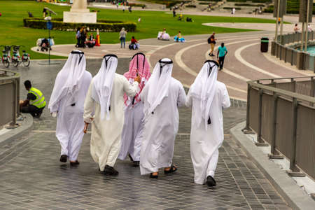 DUBAI, UAE - APRIL 5, 2020: Arabic men wearing traditional white clothes walking in Dubai downtown, United Arab Emiratesのeditorial素材