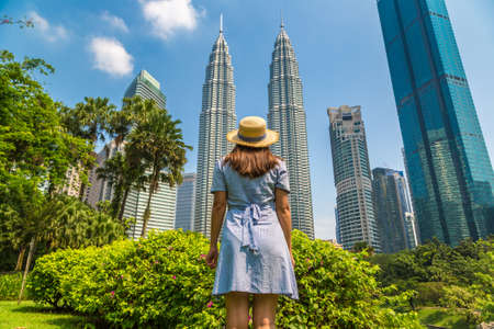 KUALA LUMPUR, MALAYSIA - FEBRUARY 25, 2020: Woman traveler at  Petronas Tower in a sunny day in Kuala Lumpur, Malaysiaのeditorial素材