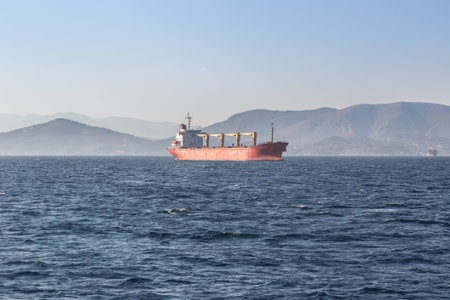 AEGINA, GREECE - JULY 19, 2015: Commercial cargo ship carrying containers in a summer day