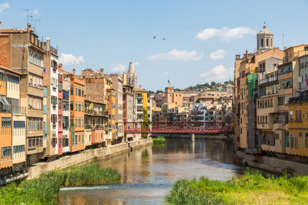 GIRONA, SPAIN - JUNE 26, 2016:  Colorful houses, Eiffel bridge and Saint Mary Cathedral at...