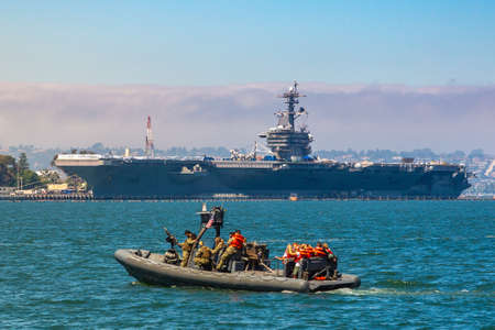 SAN DIEGO, USA - MARCH 29, 2020: Naval Base navy guard boat patrol against modern nuclear aircraft carrier in San Diego, California, USAのeditorial素材