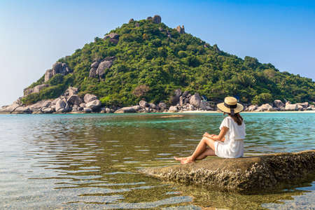 Woman traveler wearing white dress and straw hat at  Nang Yuan Island, Koh Tao, Thailand in a summer dayの写真素材