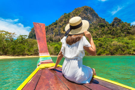 Happy traveler woman relaxing on boat near tropical islandの写真素材