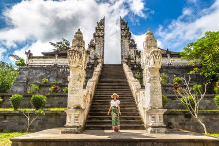 Woman traveler at Ancient gate at Pura Penataran Agung Lempuyang temple on Bali, Indonesia