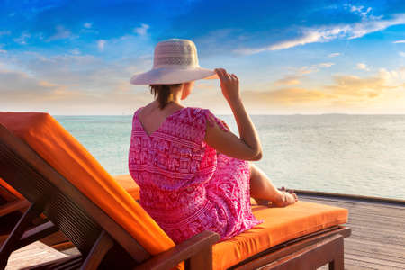 Beautiful woman relaxing in sunbed at luxury tropical beach in a sunny summer dayの写真素材