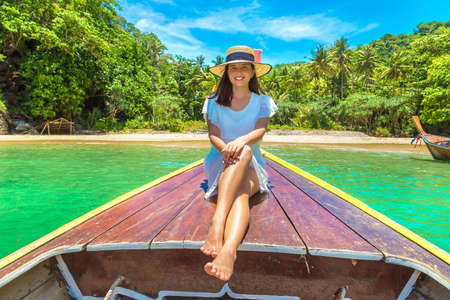 Happy traveler woman relaxing on boat near tropical island in Thailandの写真素材